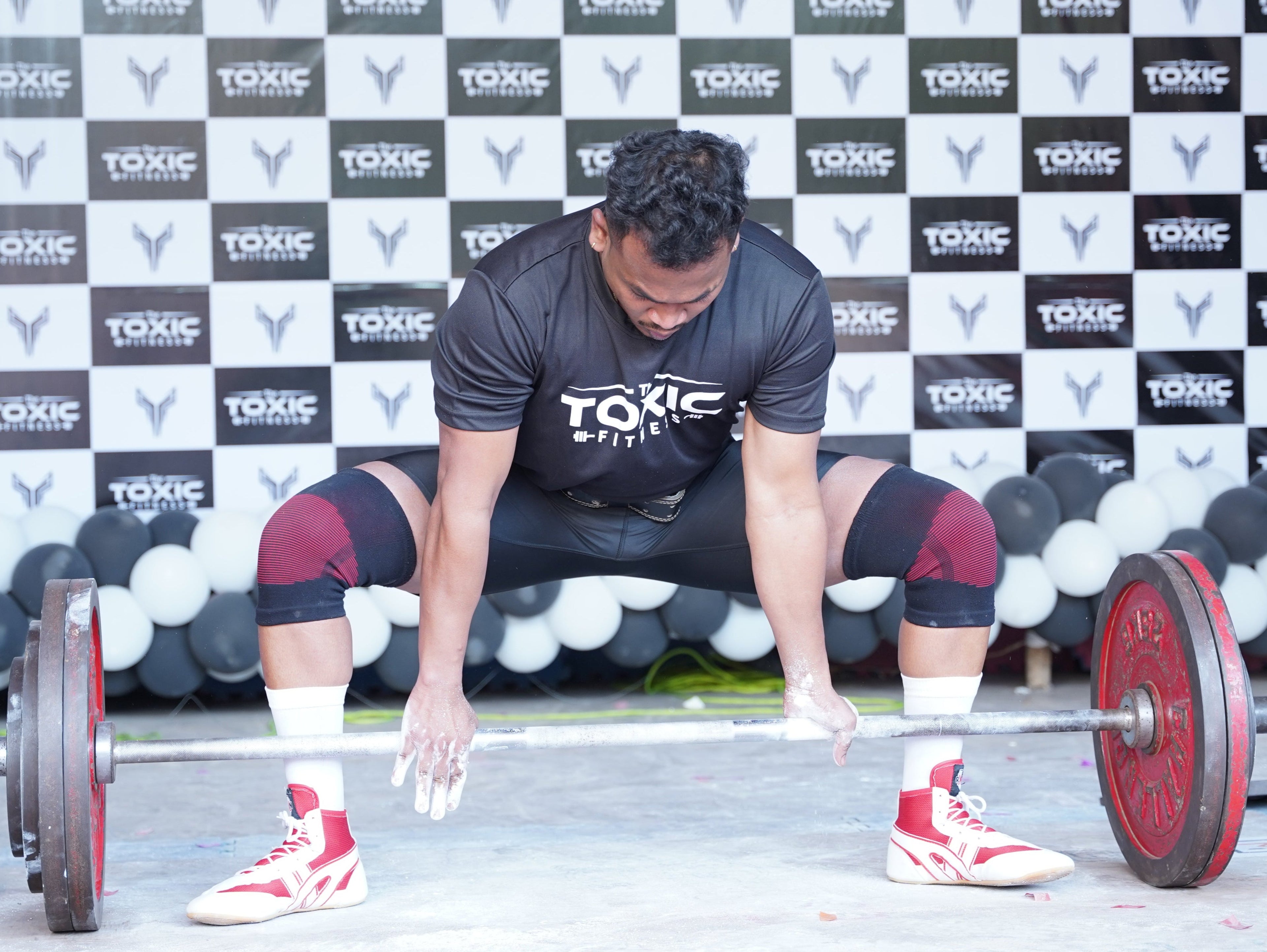 Man doing Deadlifting wearing The Toxic Fitness Signature Black Fade-Proof T shirt with the Black and White Branding of the Toxic Fitness in the Background 